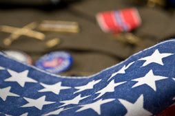 Close-up image of a folded American flag with military medals in the background, symbolizing patriotism, military sacrifice, honor, and remembrance for U.S. veterans and service members.