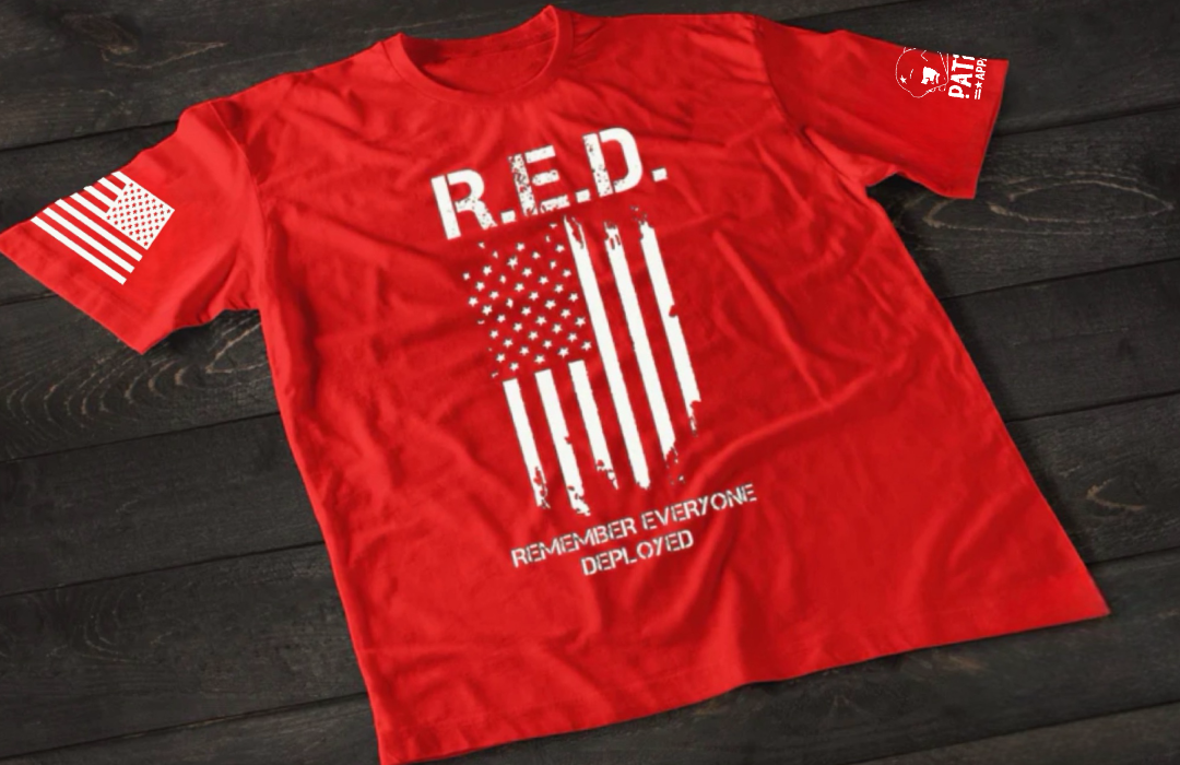 Red patriotic R.E.D. t-shirt from Patriot Apparel featuring a distressed American flag graphic and the message “Remember Everyone Deployed,” designed to honor deployed U.S. military service members and support patriotic Americans.